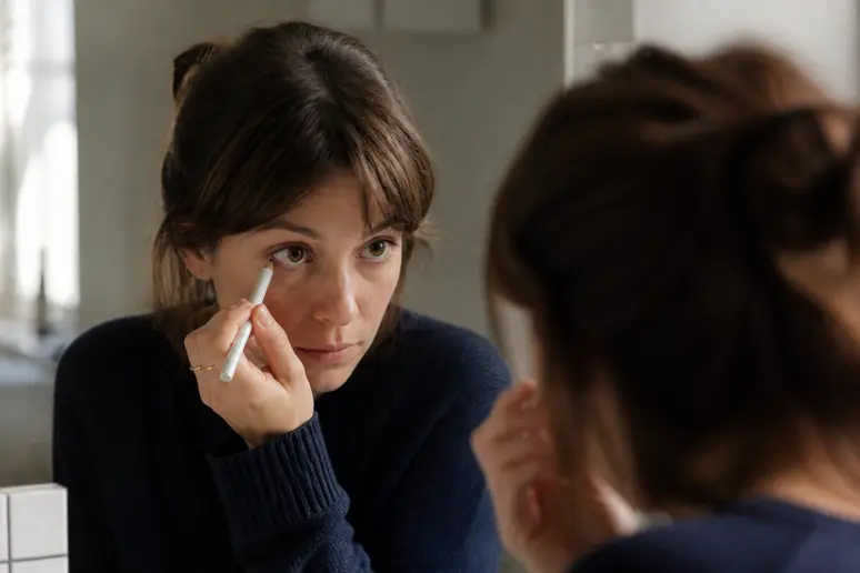 Une femme parisienne applique un crayon blanc sur sa ligne de cils inférieure pour agrandir son regard.