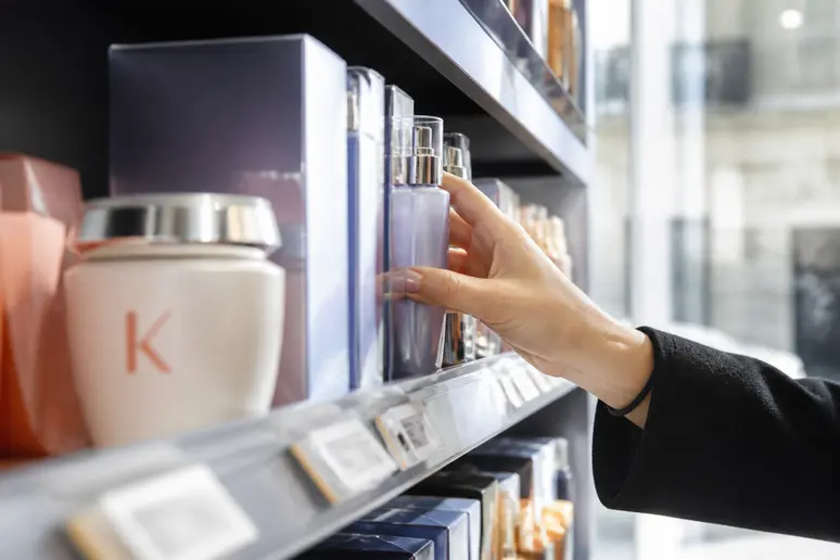 Une étagère de pharmacie parisienne présente des soins capillaires de luxe, avec un aperçu d'une crème Kérastase et son prix est suggéré.