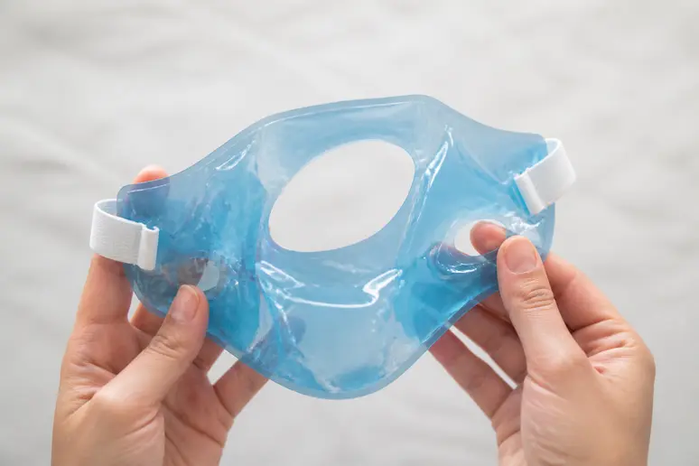 Gros plan sur les mains tenant un masque réfrigérant mâchoire, soulignant le confort et l'ergonomie.