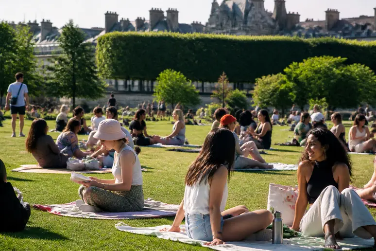 Personnes profitant d'un parc parisien, vérifiant l'indice UV pour bronzer en toute sécurité.