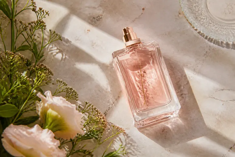 Flacon de parfum pour femme aux notes florales posé sur un comptoir en marbre beige