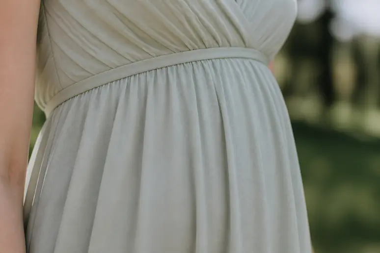 Détail d'une robe empire : le tissu tombe fluidement sous la poitrine, allongeant la silhouette.