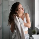 Jeune femme se préparant le matin en utilisant des astuces coiffage rapide dans sa salle de bains
