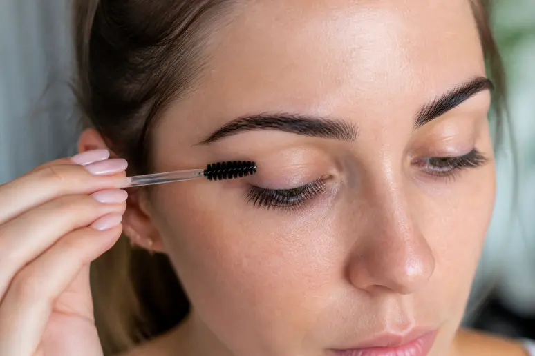 Application minutieuse d'huile de ricin sur les cils avec un goupillon propre