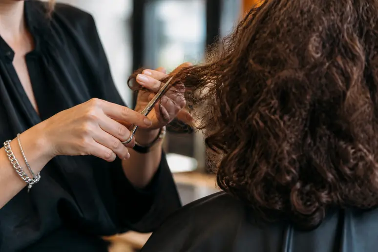 Coiffeur coupant à sec des mèches de cheveux frisés pour structurer le volume