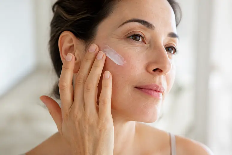 Application d'une noisette de crème hydratante Embryolisse sur le visage par effleurages légers