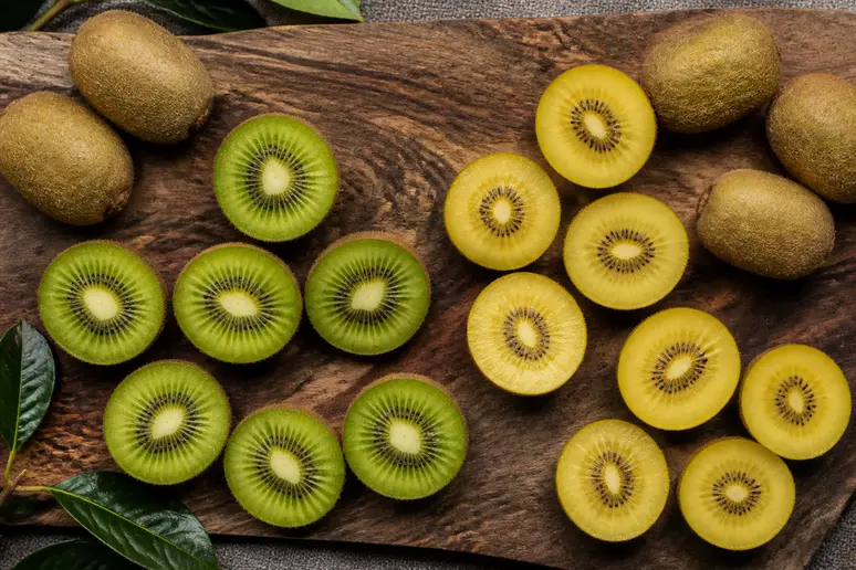 Tranches de kiwis verts et jaunes présentées sur une planche en bois pour illustrer la consommation avec la peau