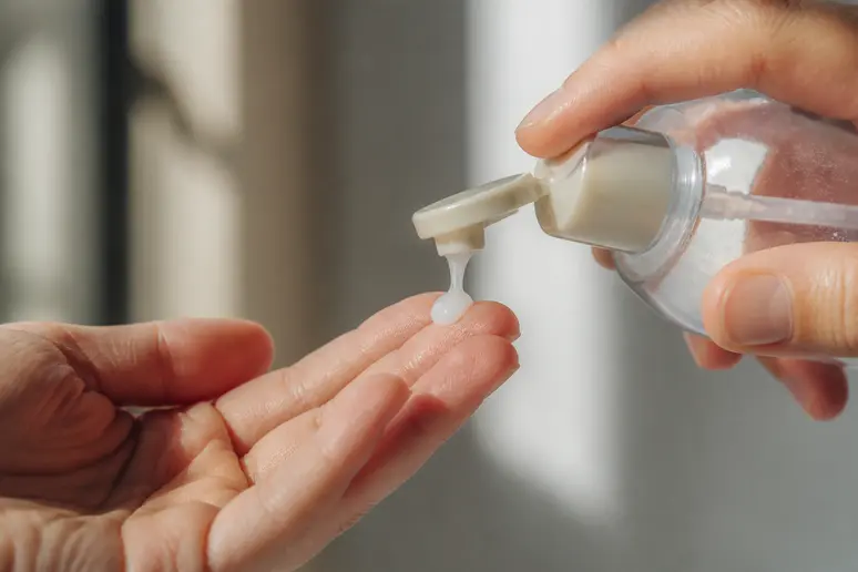 Flacon de shampooing et observation de la texture d'un soin capillaire Monat sur les doigts