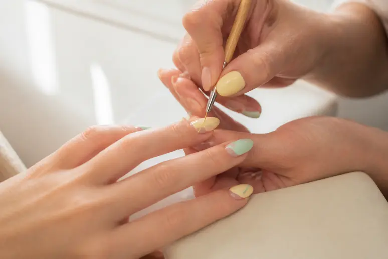 Application de nuances pastel et de motifs pour les tendances nail art d'été.