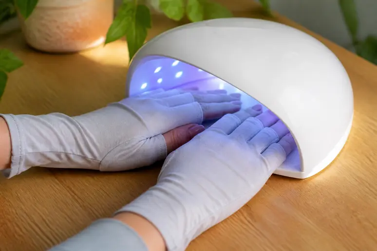 Utilisation d'une lampe UV pour vernis semi-permanent avec des gants de protection.