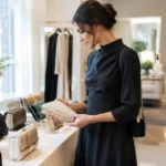 Une femme élégante choisit une pochette mariage femme sur un étalage chic.