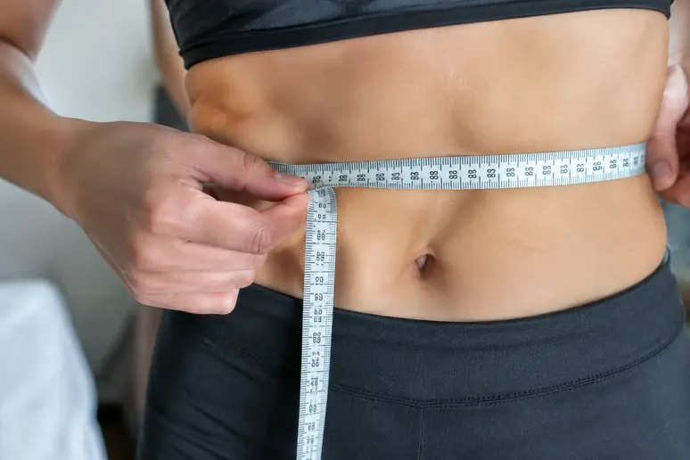 Mains mesurant le tour de taille avec un ruban souple pour choisir une robe mariage grande taille